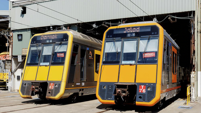 A picture of a couple of Sydney T set trains parked in a workshop. On top of their displays one reads Darmok, the other Jalad.